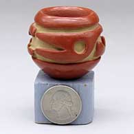 A miniature red bowl carved with a stylized avanyu design around the shoulder
 by Teresita Naranjo of Santa Clara