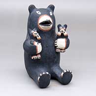 A sitting bear storyteller figure holding two cubs
 by Seferina Ortiz of Cochiti