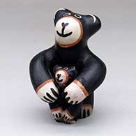 A small standing bear figure holding one cub
 by Virgil Ortiz of Cochiti