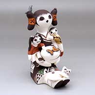 A sitting grandmother storyteller figure with two children, a pot, a cat, a butterfly, lady bugs and a bird
 by Judy Lewis of Acoma