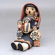 A sitting grandmother storyteller figure wearing a manta with four children, a drum and a welcome basket
 by Linda Lucero Fragua of Jemez