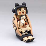A polychrome sitting grandmother storyteller figure wearing a manta and holding one child with a puppy
 by Chrislyn Fragua of Jemez