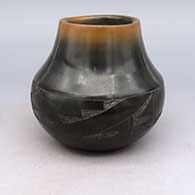 A brown jar with a sienna rim and decorated with a sgraffito and micaceous black geometric design