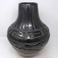 A large black jar carved with an avanyu, feather and geometric design