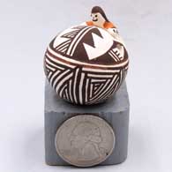 A miniature seed pot deocrated with a geometric design and an applique of a child climbing on it