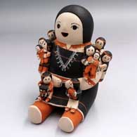 A sitting grandmother storyteller figure with 10 tiny babies