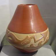Avanyu design carved into a red and tan jar