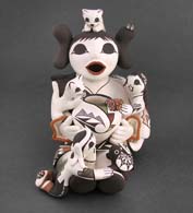 Two children on an Acoma grandmother storyteller figure with an assortment of gifts and household pets