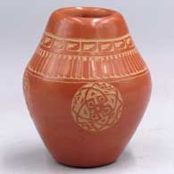 A red jar with a 4-panel sgraffito geometric design