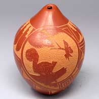 Red seed pot with a sgraffito medallion with a squirrel, a butterfly and a pine branch surrounded by a feather and geometric design
 by Vangie Tafoya of Jemez