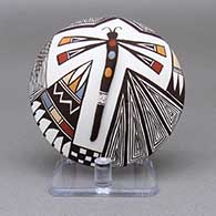 Polychrome seed pot with an applique and painted dragonfly, fine line, checkerboard, feather ring, and geometric design on top and a painted dragonfly detail on bottom
 by Carolyn Concho of Acoma