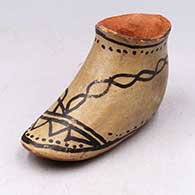 Brown moccasin with black painted design
 by Unknown of Cochiti
