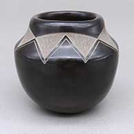A black jar with a sgrafitto triangular design in a necklace around the base of its neck