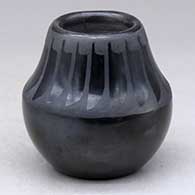 A small black on black jar decorated with a band of feathers design above the shoulder