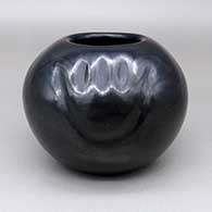 A black bowl decorated with a two-panel carved bear paw design