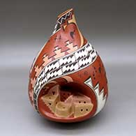A polychrome jar with an organic opening and decorated with a sculpted pueblo inset plus kokopellis, medallions and geometric designs