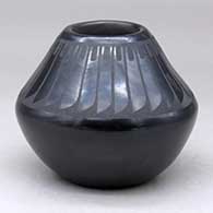 A black on black jar decorated with a band of feathers design above the shoulder