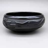 A black bowl with a carved avanyu design