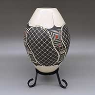 A polychrome jar with a painted geometric design and circular cut-out details