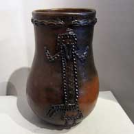 A brown cylinder decorated with fire clouds and brown button appliques in shapes and patterns