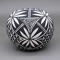 A black-on-white seedpot decorated with a fine line and geometric design