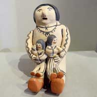 A sitting grandfather storyteller figure holding two children in his lap