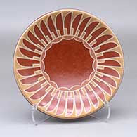 A shallow polychrome bowl decorated with a ring of feathers and geometric design