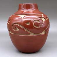 A red water jar decorated with a carved stylized avanyu design around the shoulder