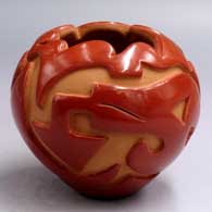 A red jar with a scalloped rim and carved with an avanyu and geometric design