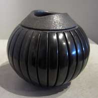 Carved black melon bowl with an organic opening and micaceous slip around the rim