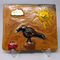 A polychrome tile decorated with a raven, sun and nature design