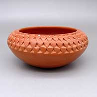 A red bowl decorated with a corrugated texture design above the shoulder