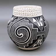 A black on white jar with a corrugated neck and decorated around the body with a three panel Tularosa spiral, fineline, kiva step and geometric design