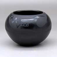 A black on black bowl decorated with an avanyu design above the shoulder