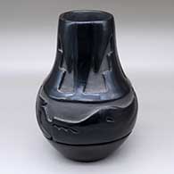 A black jar decorated with a carved avanyu and kiva altar design