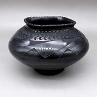 A black-on-black jar with a flared, square opening and an indented and painted geometric design