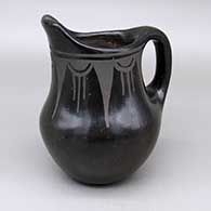 A black-on-black pitcher decorated with a geometric design