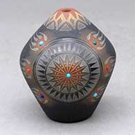 A small black seed pot with a sienna rim and spots, inlaid stones and a sgraffito bear paw and geometric design