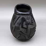 A black jar with an asymmetrical opening and a carved kokopelli and geometric design