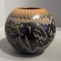 Sgraffito avanyu, feather and geometric design on a black jar with sienna rim and spots