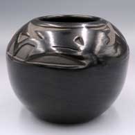 A black jar carved with an avanyu design