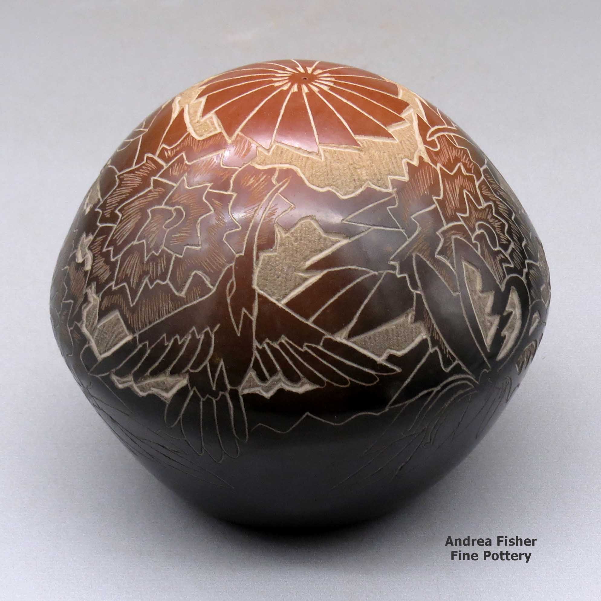 Click or tap to see a larger view A black seed pot with a large sienna spot and decorated with a sgraffito hummingbird, flower, leaf, vine and geometric design made by Eric Tafoya of Santa Clara