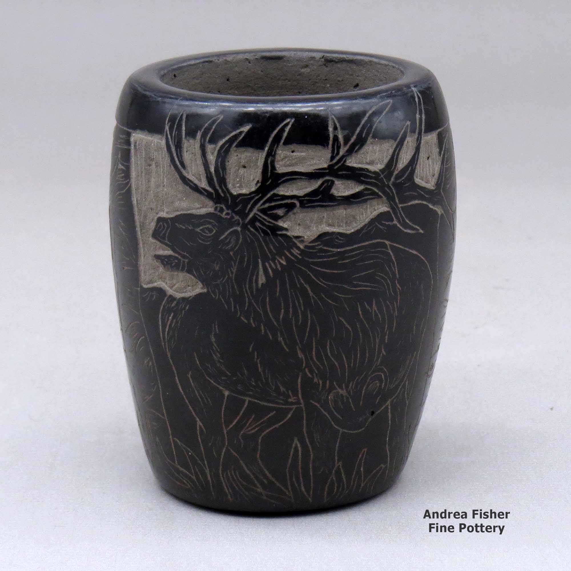 Click or tap to see a larger view A small black jar decorated with a sgraffito elk and nature design made by Martin Moquino of Santa Clara