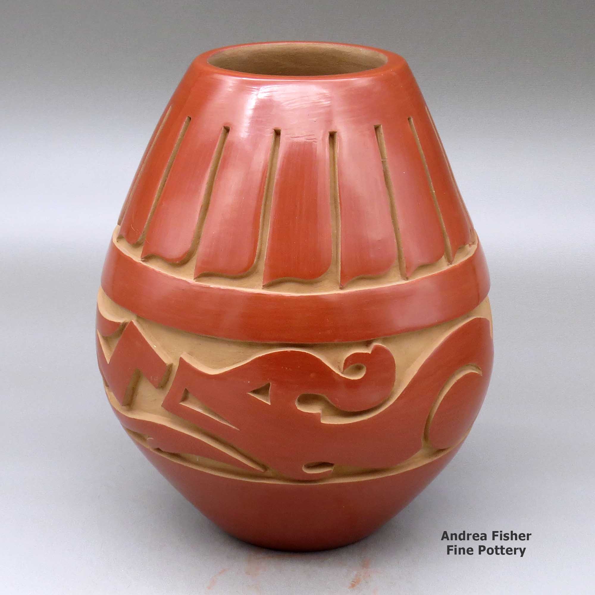 Click or tap to see a larger view A red jar carved around the body with an avanyu and feather design made by Kimberly Garcia of Santa Clara