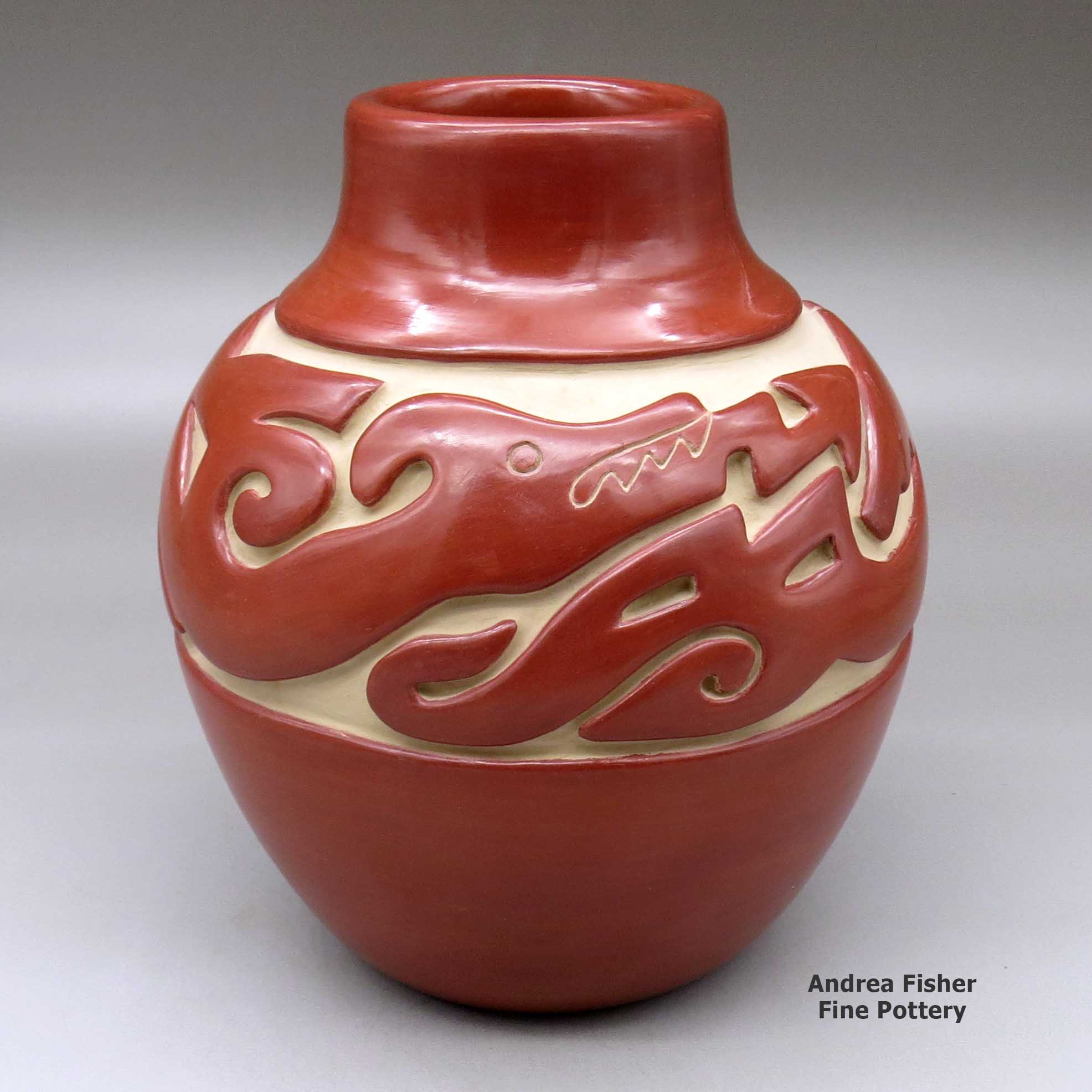 Click or tap to see a larger view A red jar carved around the shoulder with an avanyu and geometric design made by Jennie Trammel of Santa Clara