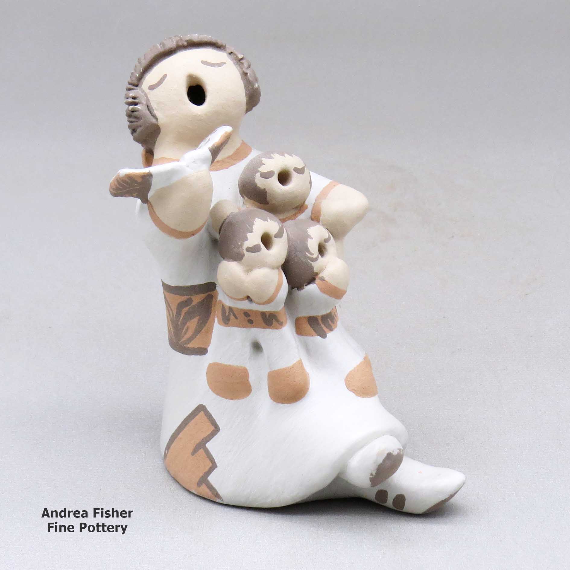 Click or tap to see a larger view A grandmother holding a math book open and singing with the three children in her lap made by Mona Teller of Isleta