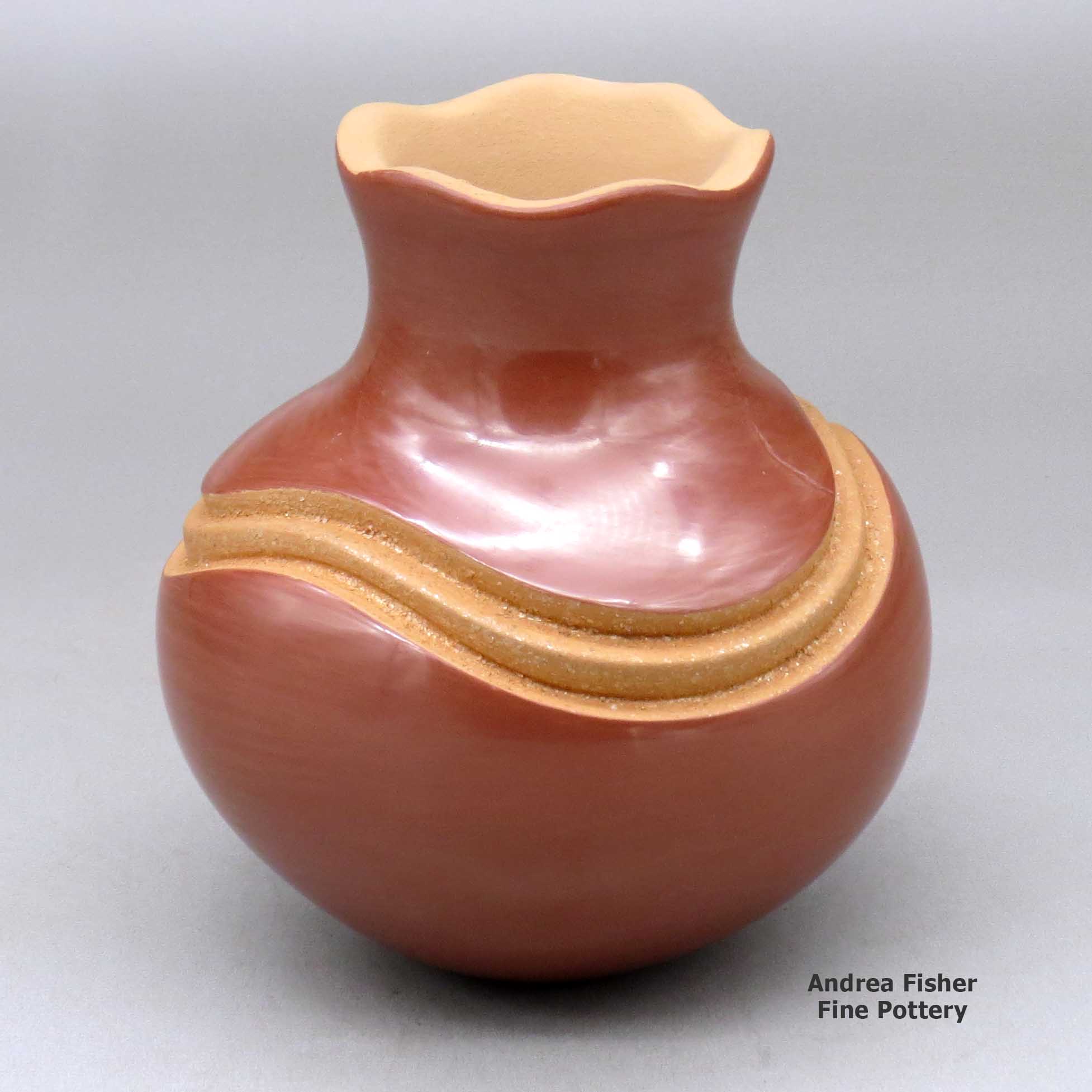 Click or tap to see a larger view A red jar with a pie crust rim and decorated with a carved geometric design painted with micaceous clay made by Dominique Toya of Jemez