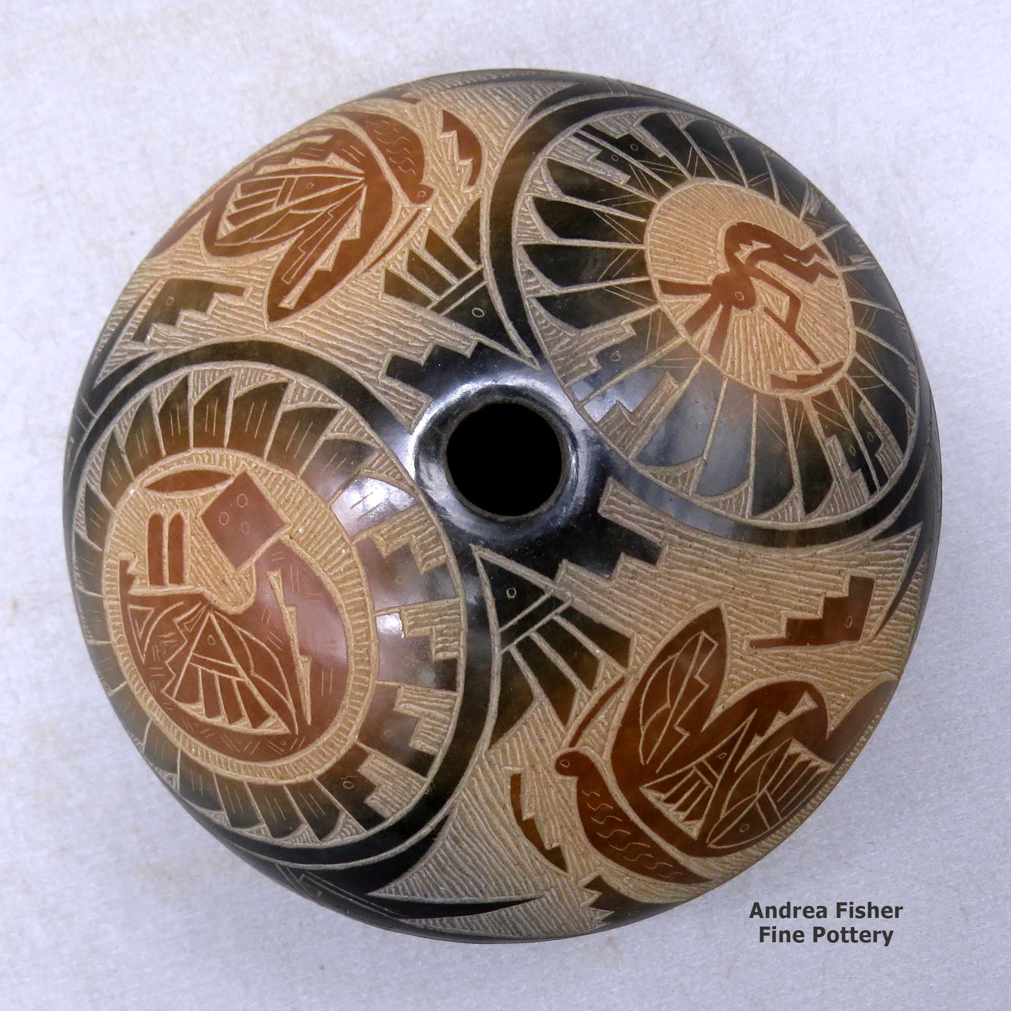 Click or tap to see a larger view A black seed pot with sienna spots and a sgraffito medallion, kokopelli, yeibichai, butterfly and geometric design above the shoulder made by Candelaria Suazo of Santa Clara