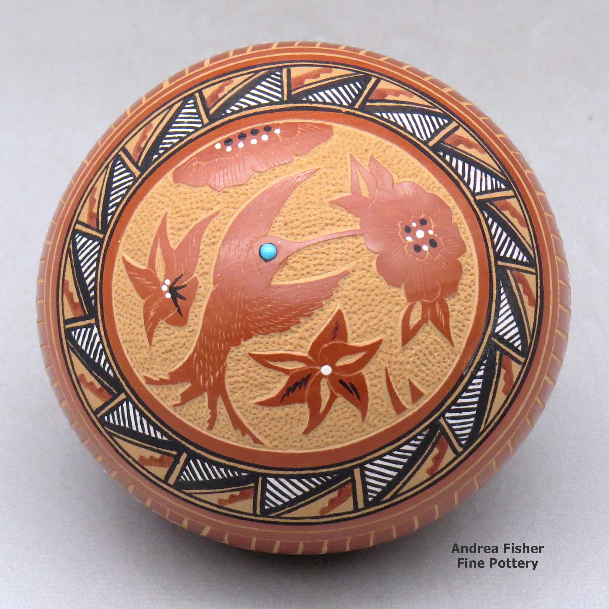 Click or tap to see a larger view A polychrome seed pot decorated with a sgraffito and painted medallion, hummingbird, flower, and geometric design, with an inlaid stone made by Helen Tafoya of Jemez