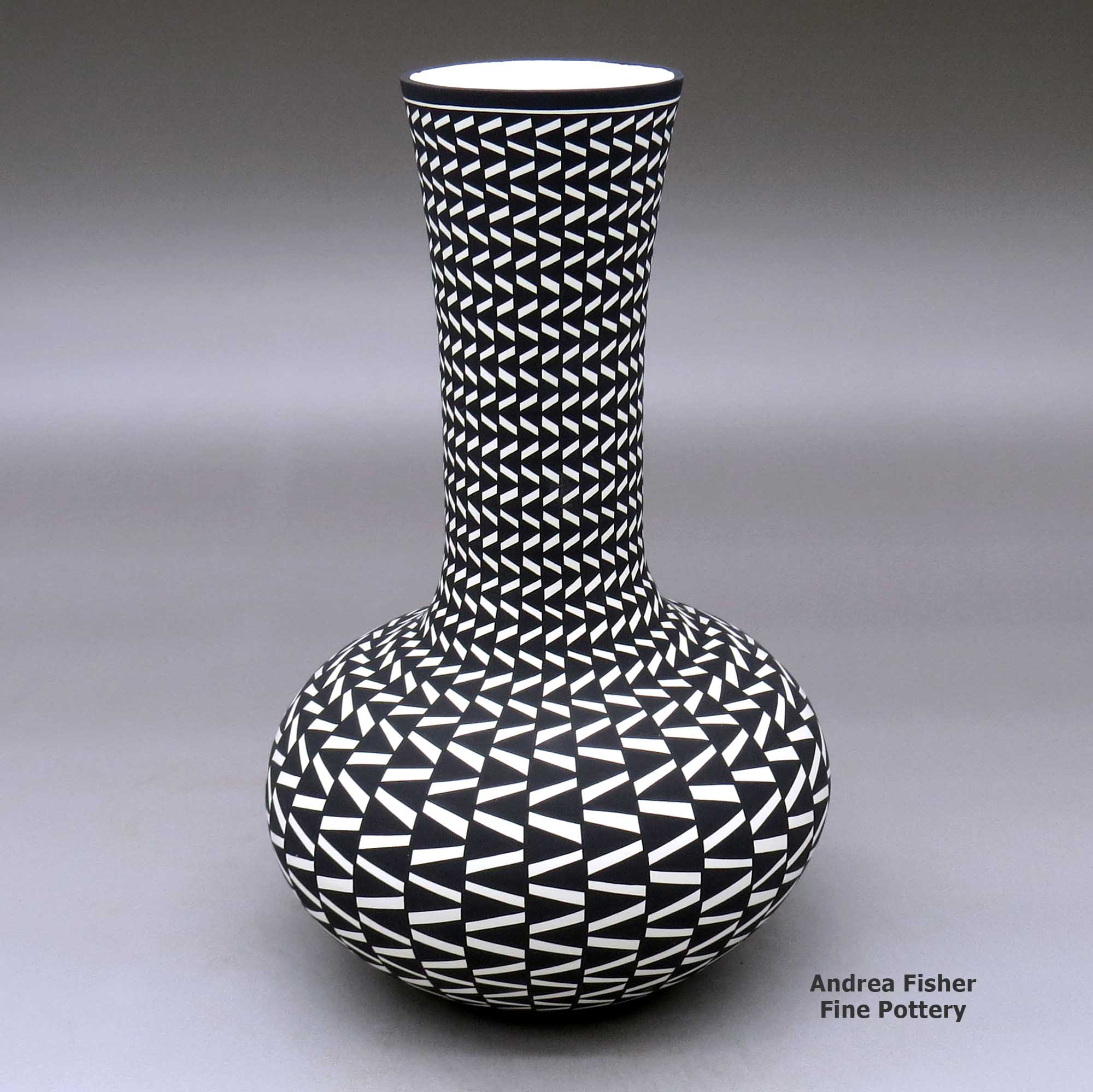 Click or tap to see a larger view A tall neck black on white vase decorated with a geometric design made by Paula Estevan of Acoma